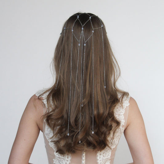 Metal bridal hair veil with delicate chains and crystals draping over hair, creating an elegant and intricate design for wedding hairstyle