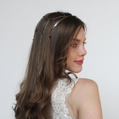 Portrait of a woman wearing a silver crown-style headband with red crystals, highlighting the accessory’s sparkle