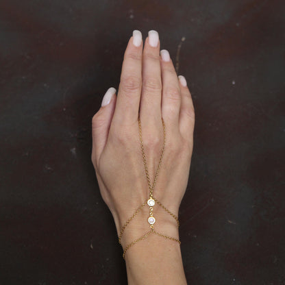 Gold chain bracelet connecting to a ring, adorned with bright sparkling white crystals, creating a stylish and elegant hand accessory